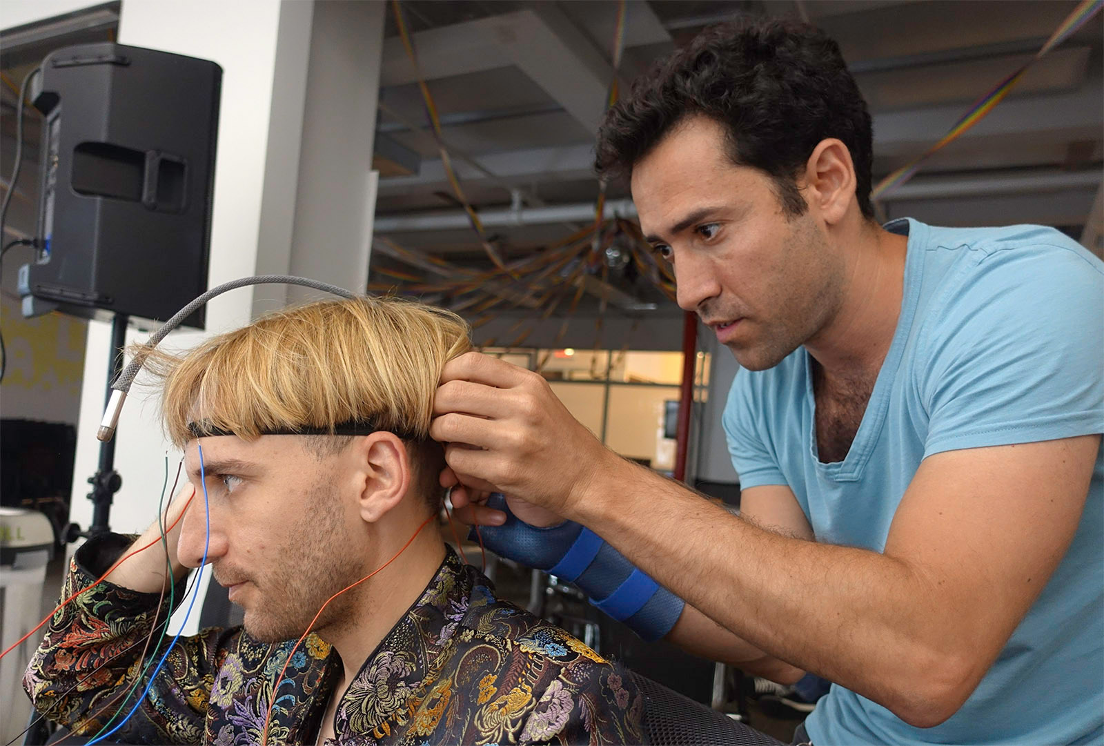 An engineer fixes a headband to artist Neil Harbisson\s head