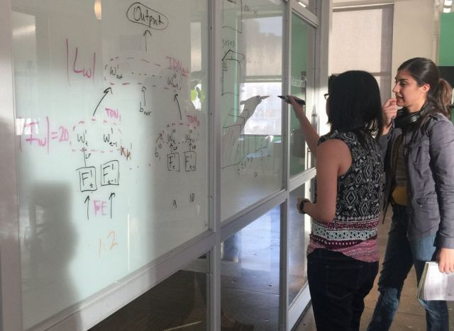 Two women working at a white board