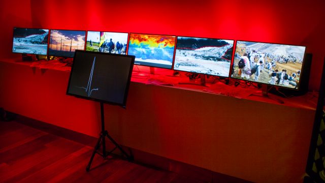 Screens showing climate chaos in a red room