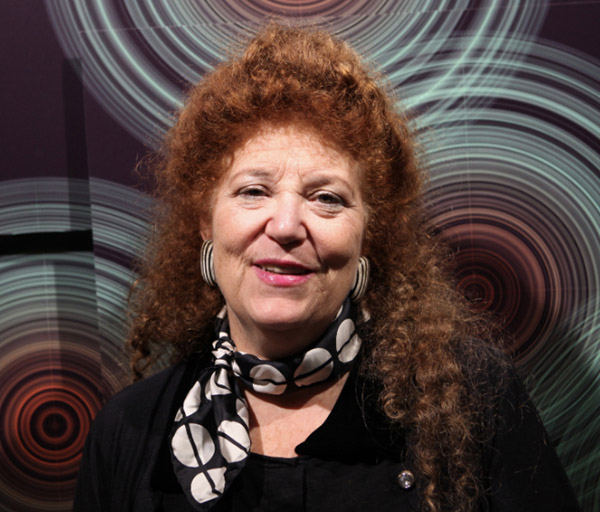 A woman with curly red hair and a scarf posing in a portrait shot