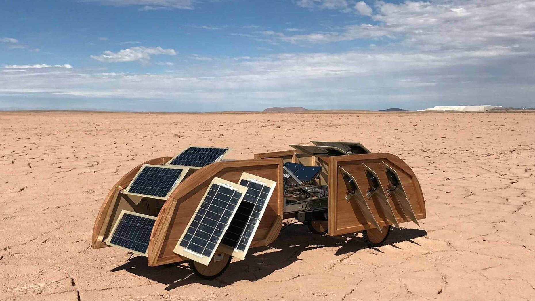 A robot with wooden sides, solar panels and wheels in a desert environment