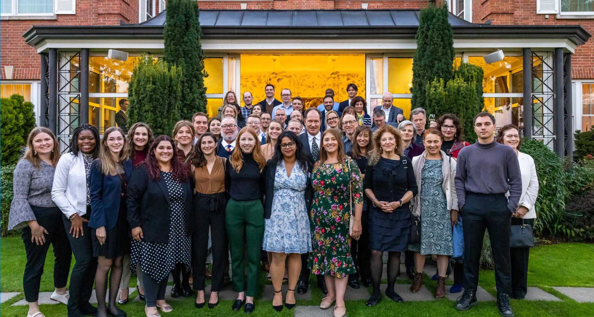 Around 45 people posing in front of a large conservatory in a garden