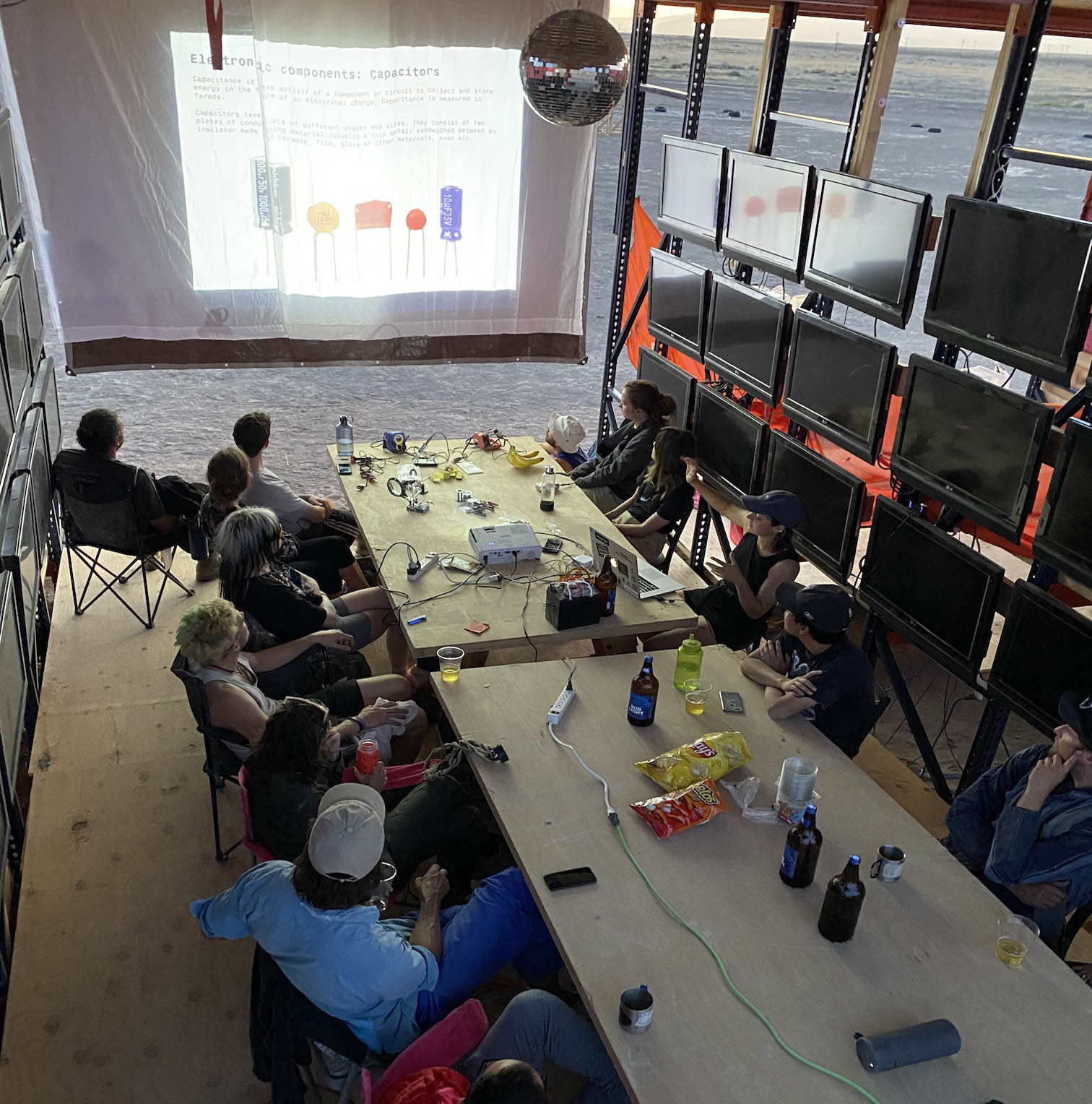 People attending an electronics workshop inside a structure in the desert