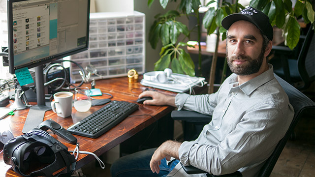 Kent Rahman sitting at a computer with electrical components in a drawer behind him