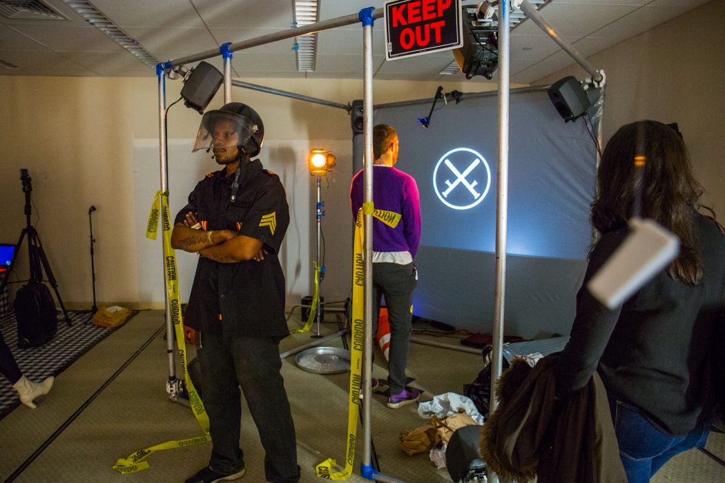 A “police officer” stands guard as vistors enter a frame box with “keep out” signs to watch a movie