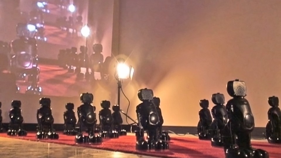 Small black robots lined in a military-style formation