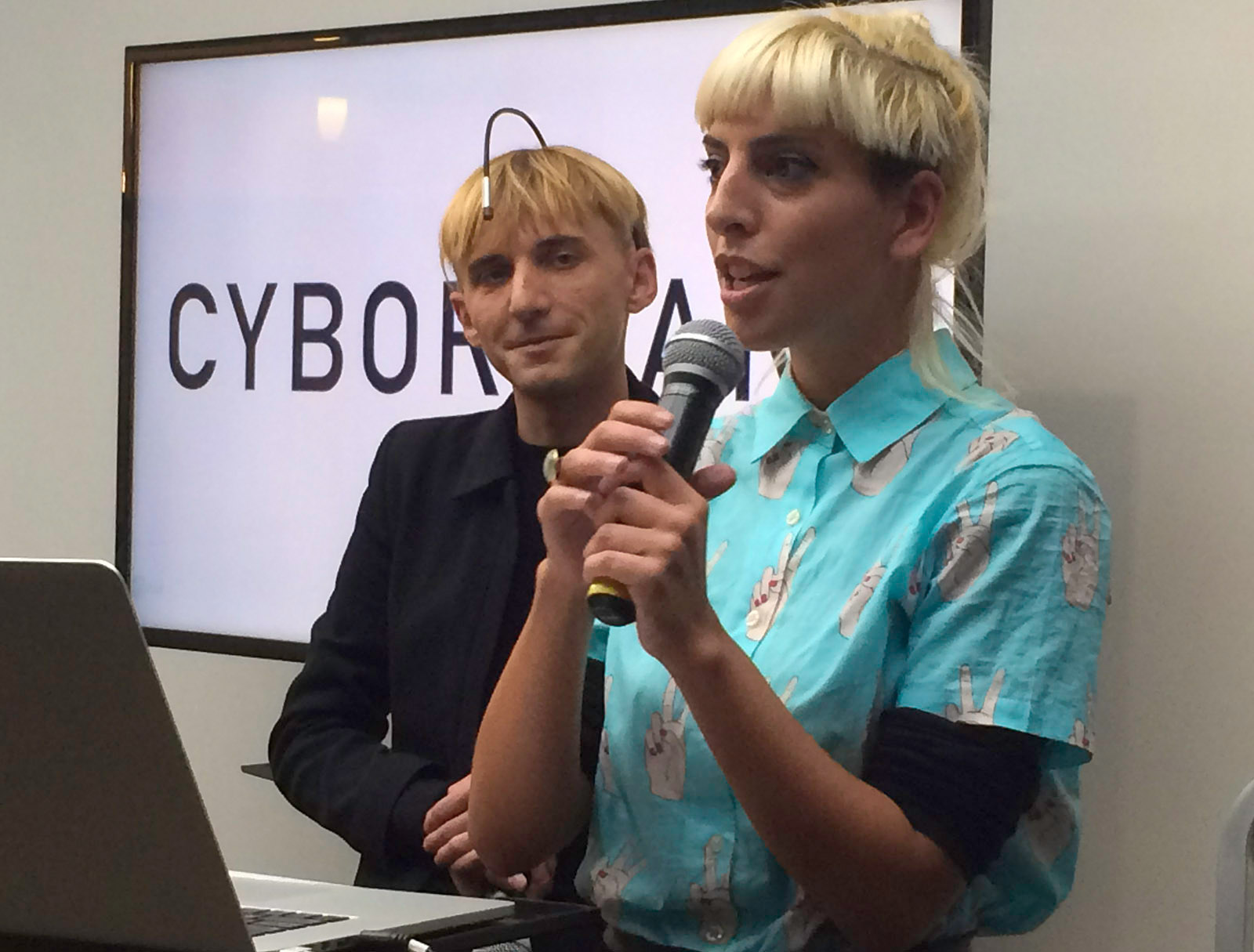 Moon Ribas speaking in front of a sign that says “Cyborg Art”