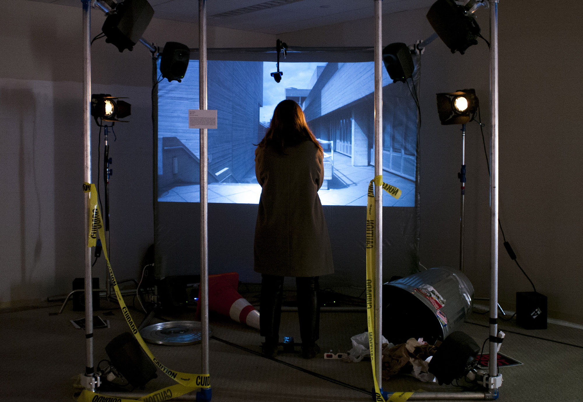 A woman stands in a dark room with a video screen in front of her