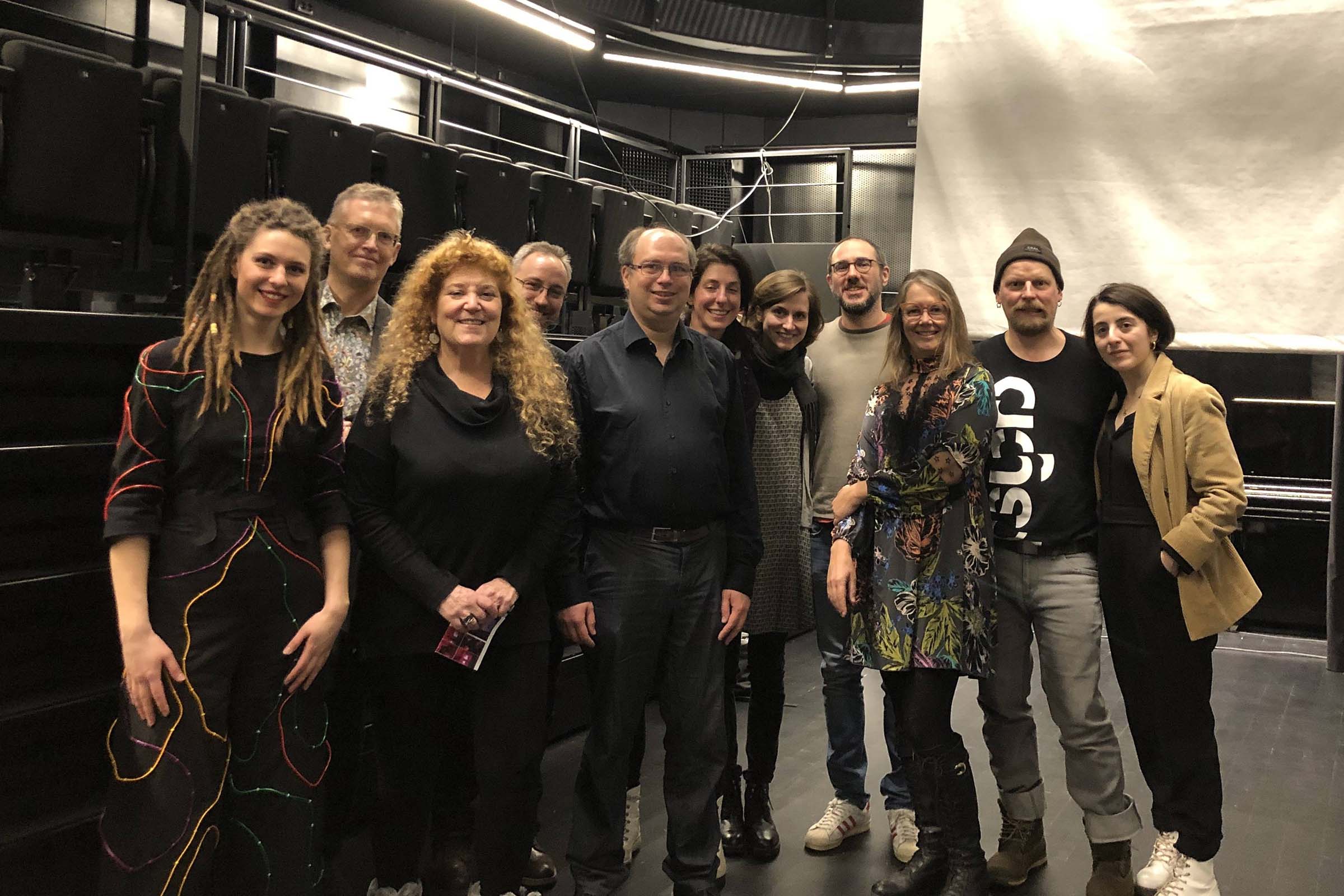 Eleven people posing in a performance studio with the lights up