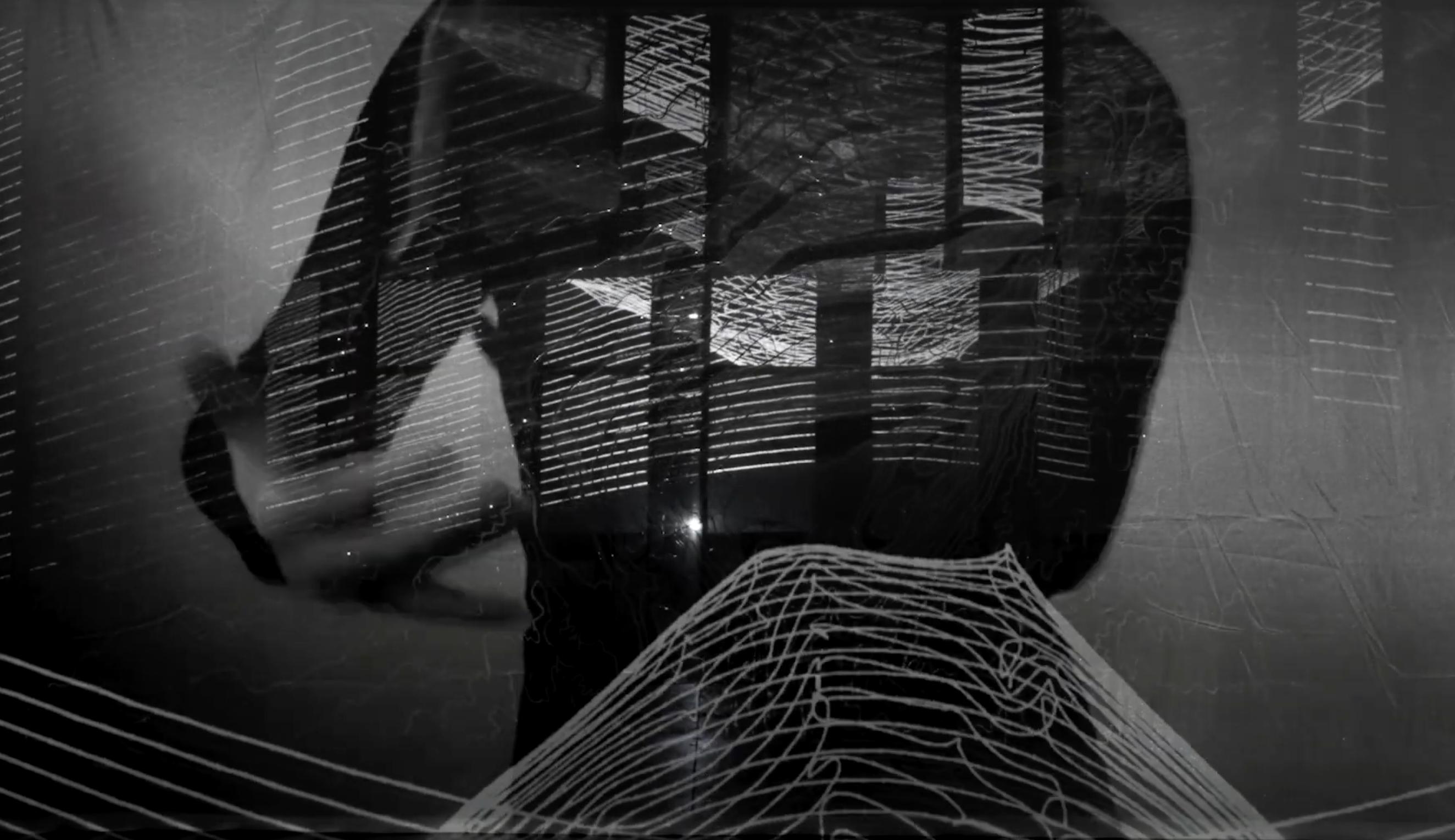 A grayscale video still with a silhouette of a human torso with waving digital lines overlaid