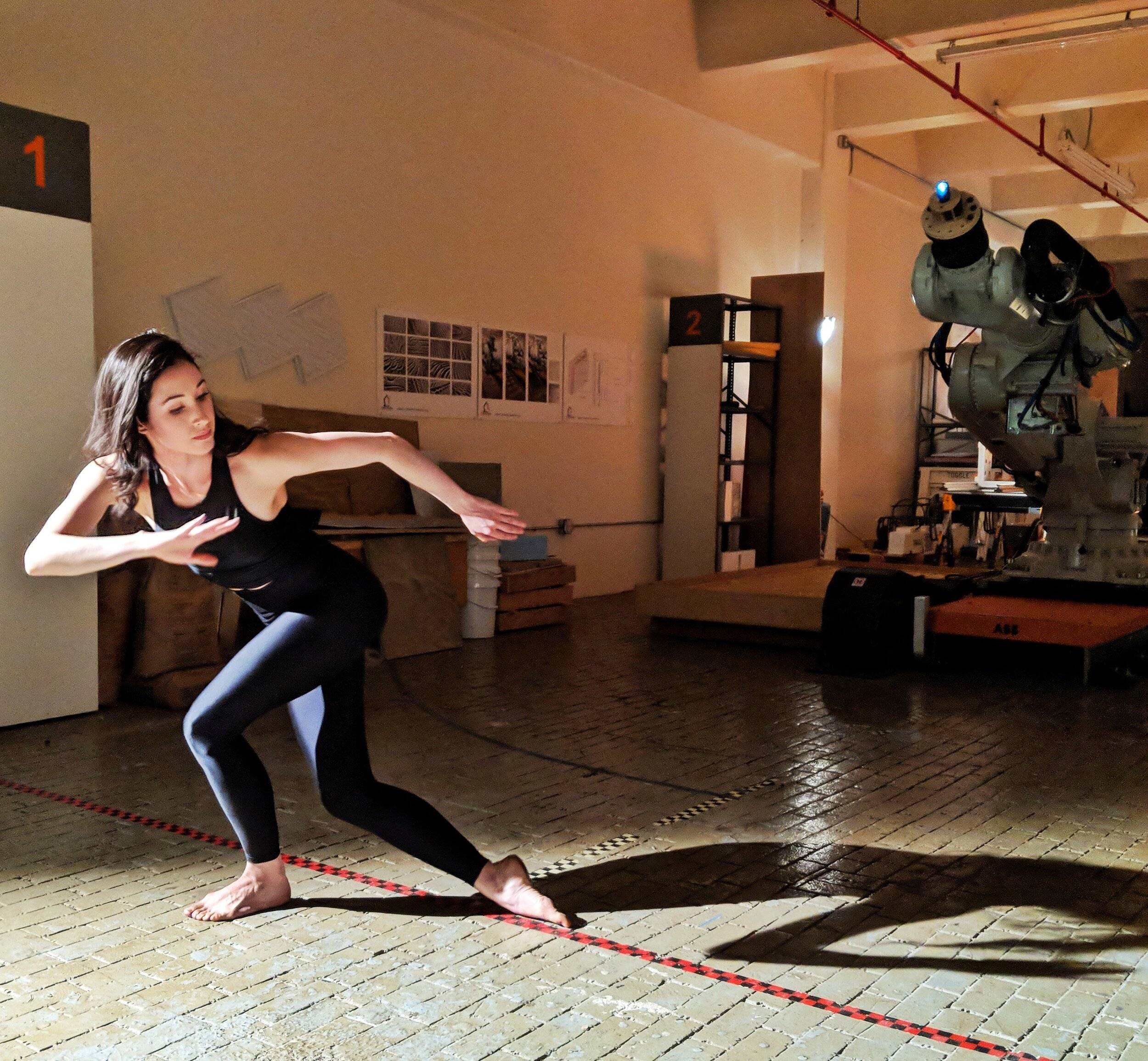 Catie dancing in front of an industrial robot