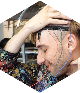 A man seen from the side with wires coming from a headband he is wearing